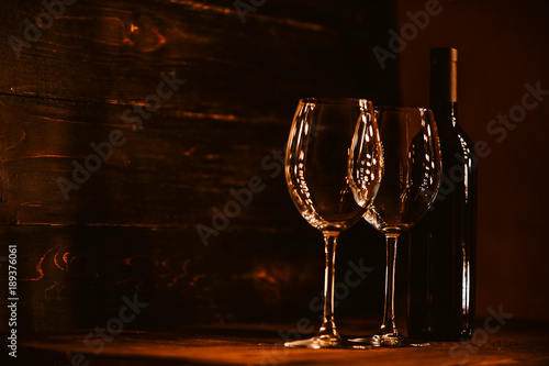 bottles with red wine and wine glasses on a wooden surface