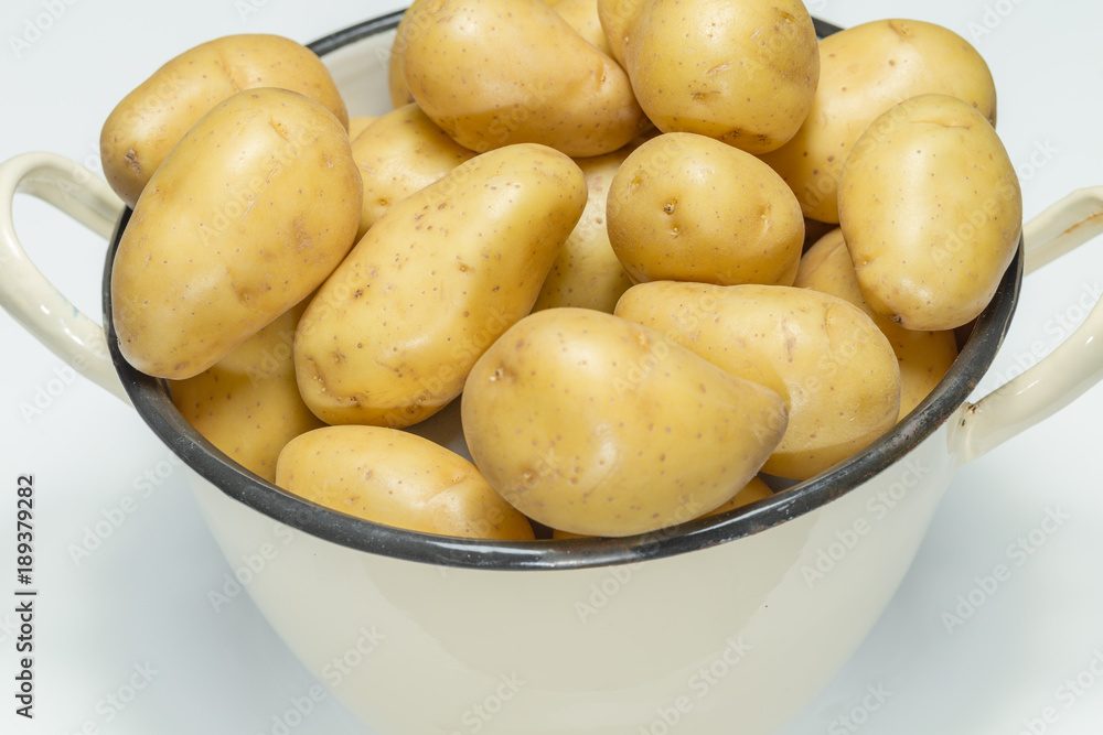 Kartoffeln mit Schale in einem nostalgischen beigen Topf auf weissem Hintergrund Kartoffeln mit Schale in einem nostalgischen beigen Topf auf weissem Hintergrund