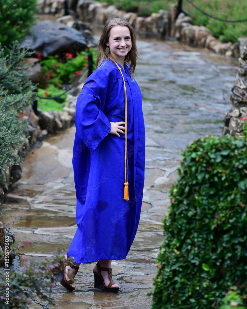 High School Senior in cap and gown posing in the rain at a botanical