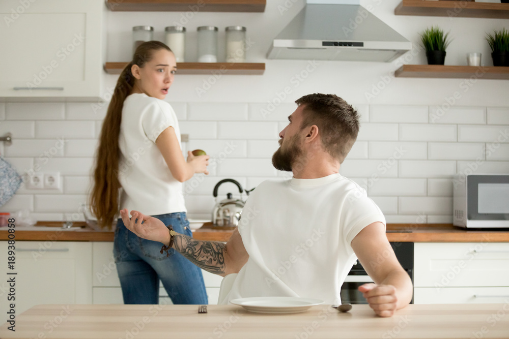 Angry husband and shocked insulted wife arguing in the kitchen, hungry mad boyfriend scolding offended girlfriend for bad cooking, unhappy couple having conflict quarrel disagree about food at home Angry husband and shocked insulted wife arguing in the kitchen, hungry mad boyfriend scolding offended girlfriend for bad cooking, unhappy couple having conflict quarrel disagree about food at home