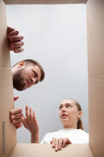 Confused customers dissatisfied with damaged broken parcel, angry couple disappointed after dispatching cardboard box with wrong order, bad delivery service and refunding concept, view from open box photo