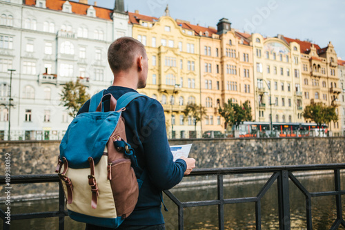 A tourist with a backpack on the backdrop of the old architecture in Prague in the Czech Republic. He looks at the map.