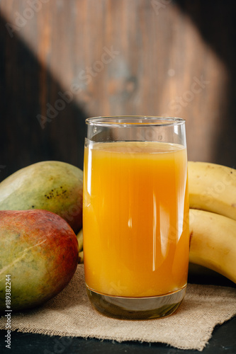 Mango and banana juice on black surface.