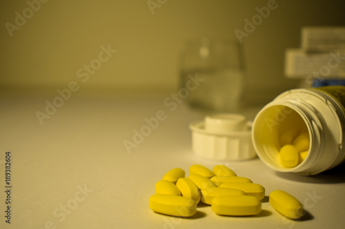 Yellow pills with a blurred boxes and glass