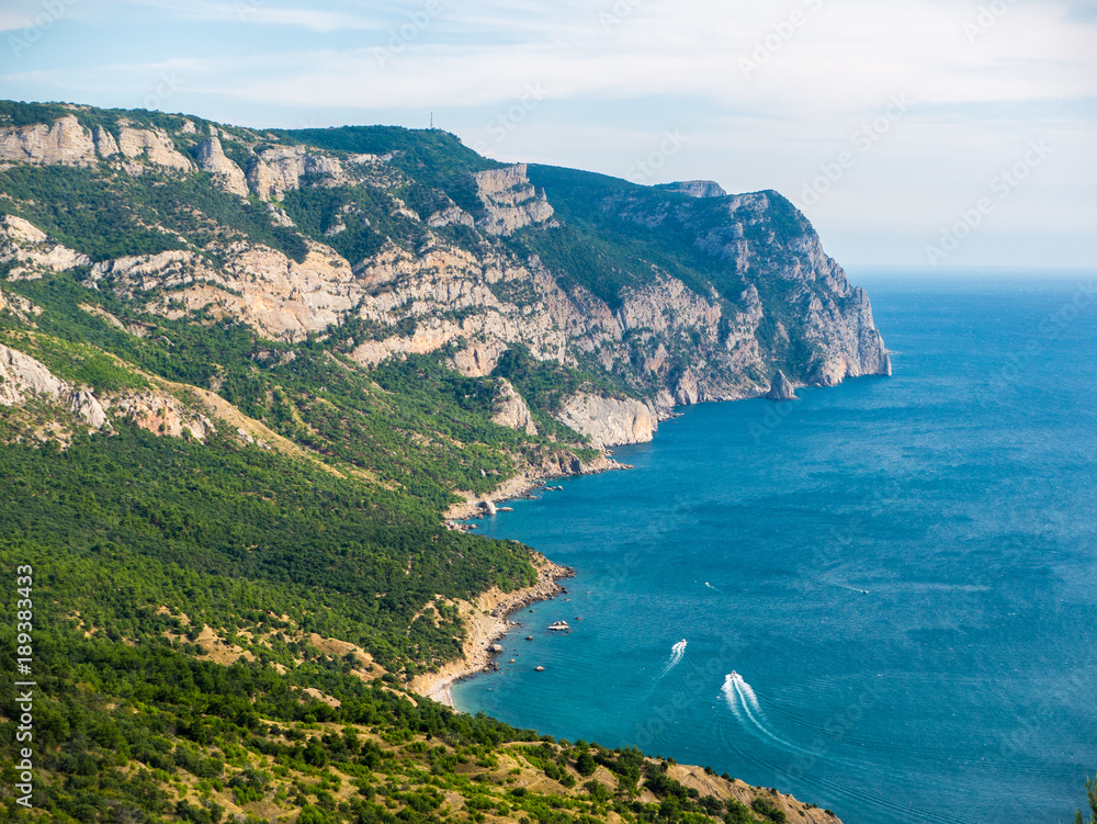 the view from the height over the sea. rocky shore and boats in the sea in sunny day. Top view of yachts. Nature background. Aerial view