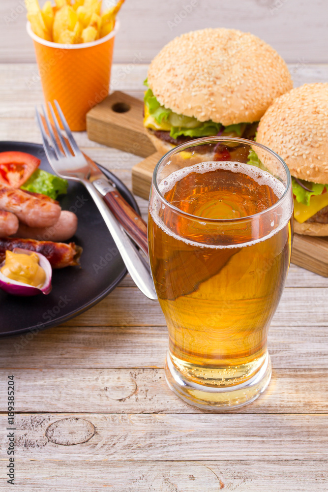 Glass of beer with burger and fries on wooden background. Beer and food concept. Ale and food. vertical Glass of beer with burger and fries on wooden background. Beer and food concept. Ale and food. vertical