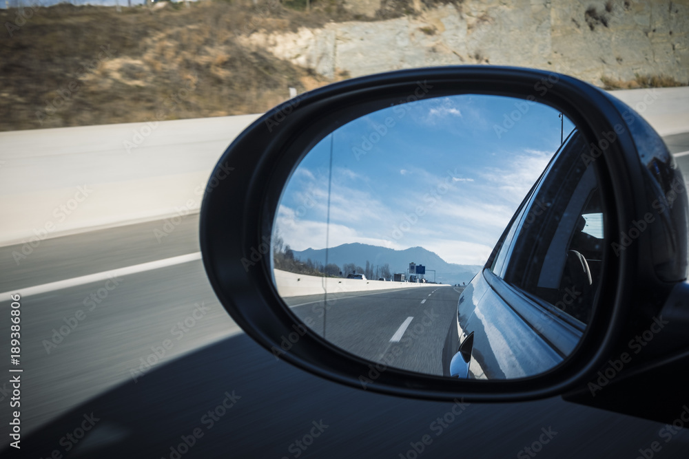 Left mirror car on a highway on a blue sky