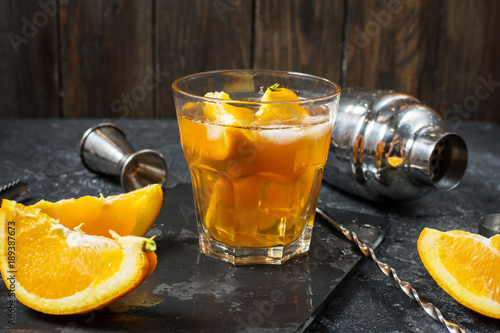 A glass of Negroni cocktail with orange and lemon. Alcoholic drink with rum and vermouth on dark stone table