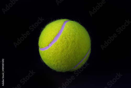 Felt tennis ball isolated on black background. Tennis ball photo for banner template. © Elya.Q