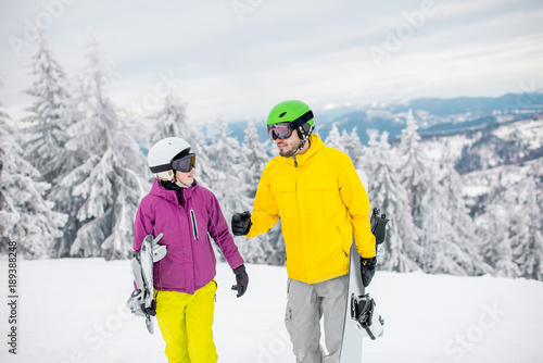 Young couple walking with snowboards during the winter vacation on the snowy mountains