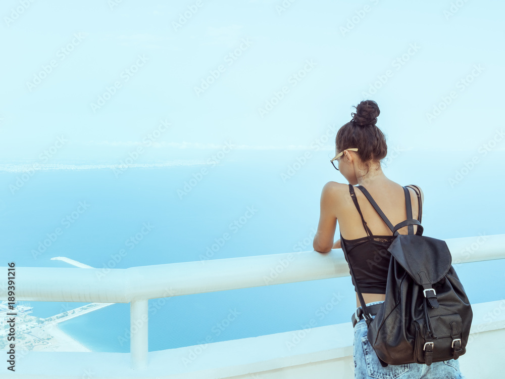 Fototapeta premium Beautiful young tourist girl with backpack near sea