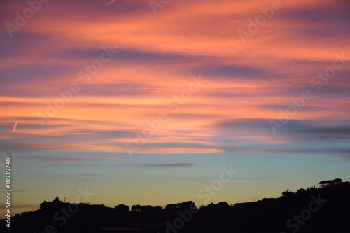 Tramonto con nuvole arancioni e rosa sulla collina © elesco16