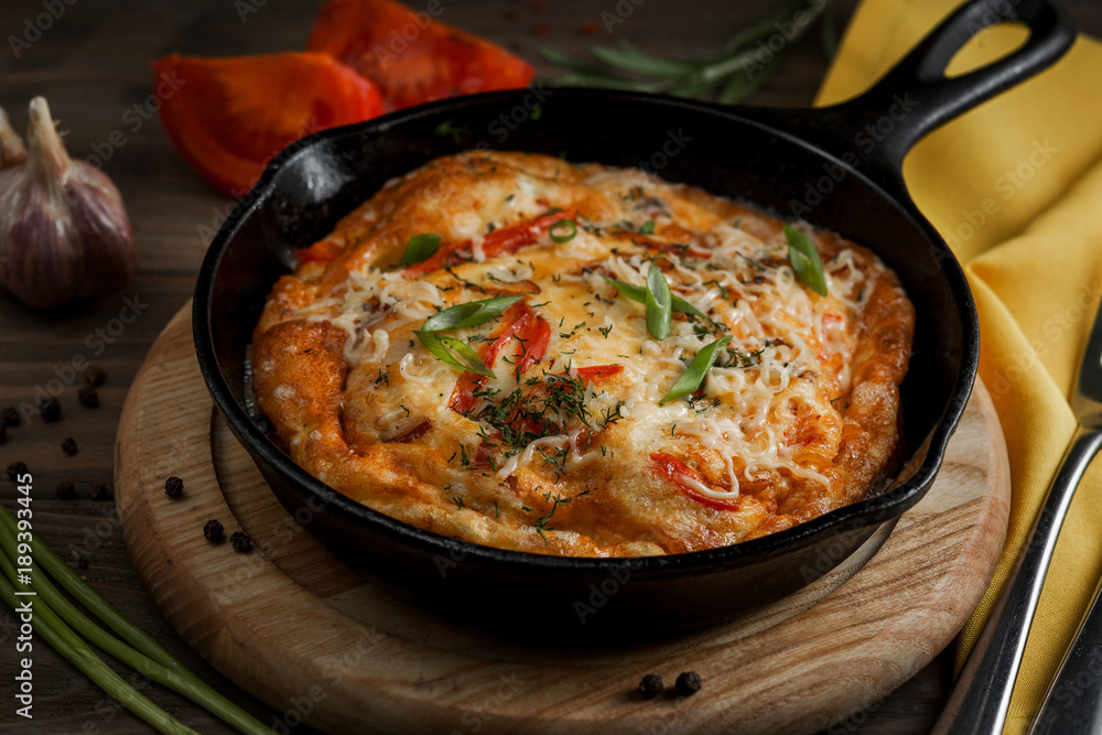 Hot pan with omelet and vegetables on a wooden table Hot pan with omelet and vegetables on a wooden table
