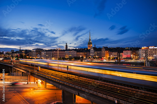 Scenic night view of Stockholm with train and light trails. Riddarholmen and Gamla Stan at night.