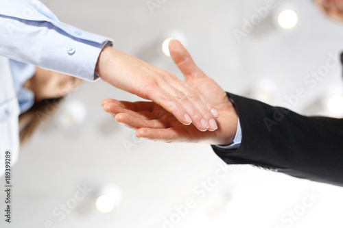 Gratulacje. Powitanie nowego pracownika firmy. Dłoń kobiety i mężczyzny w strojach biurowych podczas gestu przywitania.