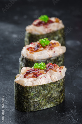 Three Gunkan maki sushi with scalop meat and sauce spice on black background photo