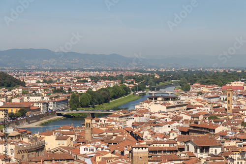 Florentine cityscape with red roofs, Arno river and hills on background in a sunny day, Tuscany, Italy.