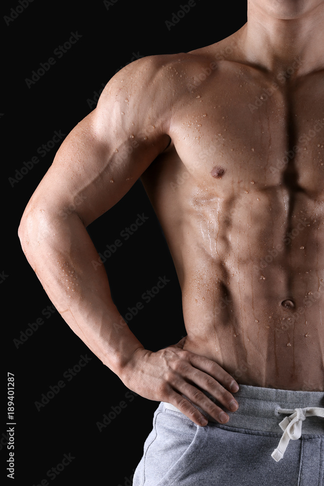 Handsome muscular young man with drops of sweat on skin against black background Handsome muscular young man with drops of sweat on skin against black background