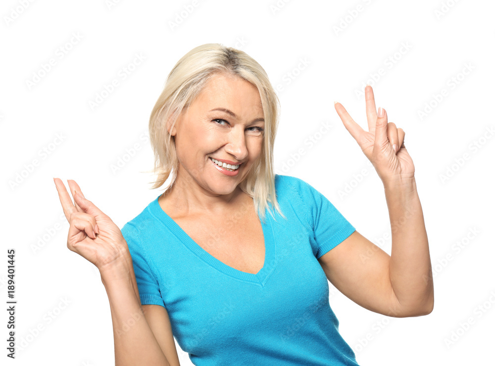 Portrait of smiling mature woman showing victory gesture on white background Portrait of smiling mature woman showing victory gesture on white background