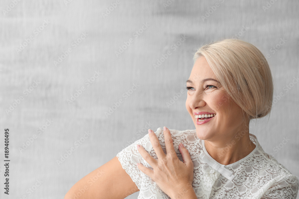 Portrait of beautiful mature woman on grey background Portrait of beautiful mature woman on grey background