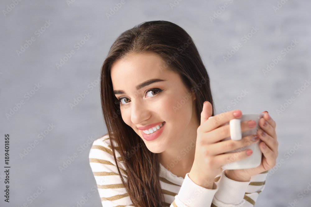 Beautiful smiling woman with cup of coffee on grey background Beautiful smiling woman with cup of coffee on grey background