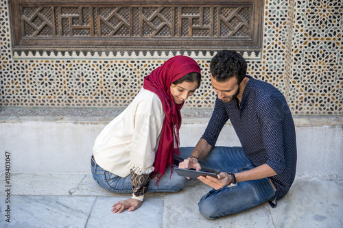 Young Arab couple in relationship working on tablet in traditional arabic ambient