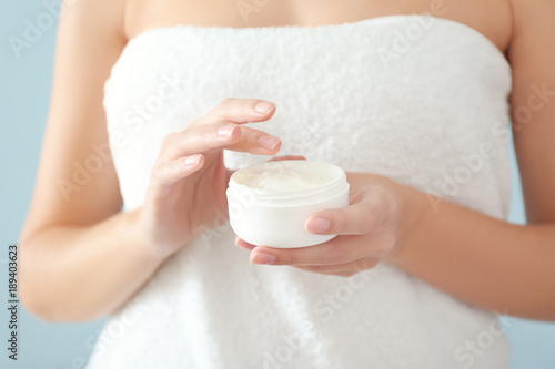 Young woman with jar of hand cream on color background, closeup