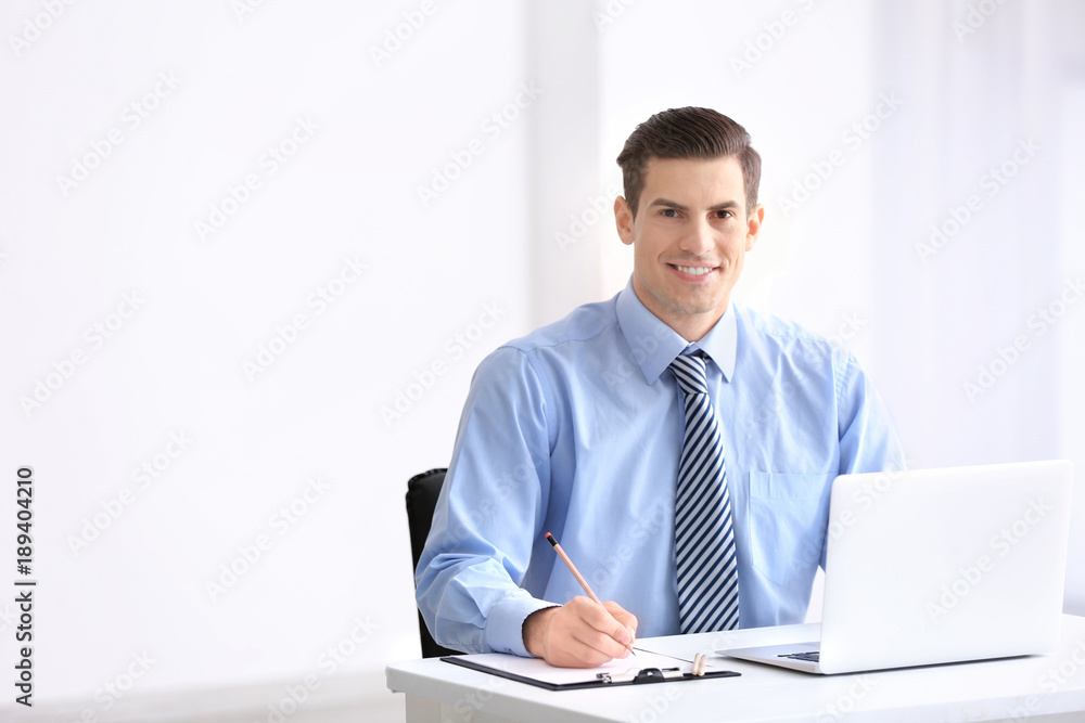 Young man in office wear using laptop indoors Young man in office wear using laptop indoors