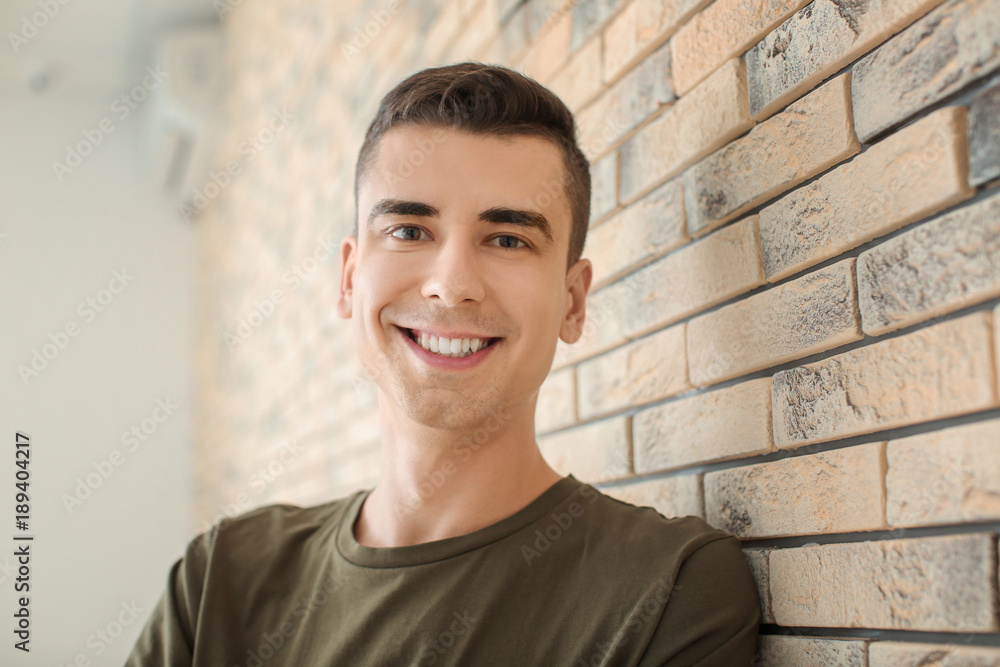 Obraz premium Portrait of young man in casual clothes near brick wall