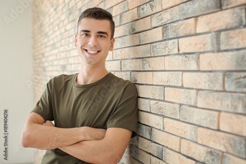 Portrait of young man in casual clothes near brick wall © Africa Studio