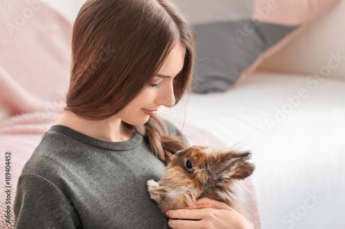Beautiful young woman with pet rabbit at home