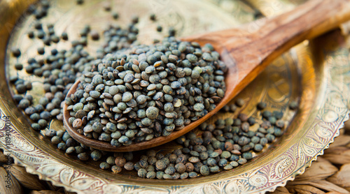 Puy Lentils -  French Green legume, dried grains on wooden spoon.