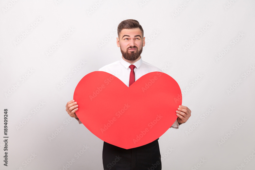 Bearded man thoughtful, holding red heart and thinking of love Bearded man thoughtful, holding red heart and thinking of love