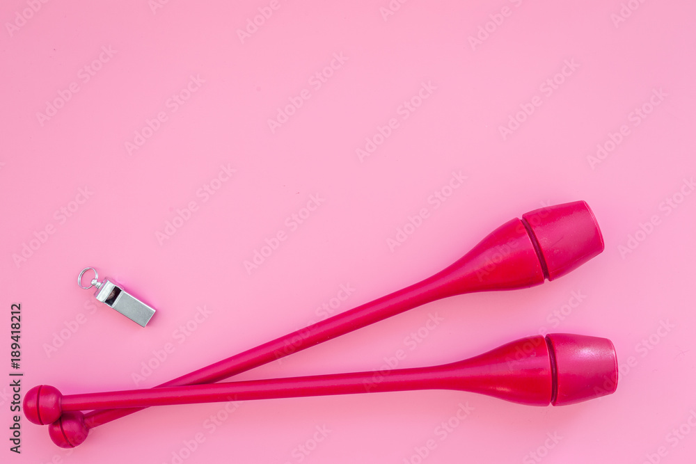 Equipment for rhythmic gymnastics. Clubs on pink background top view copy space