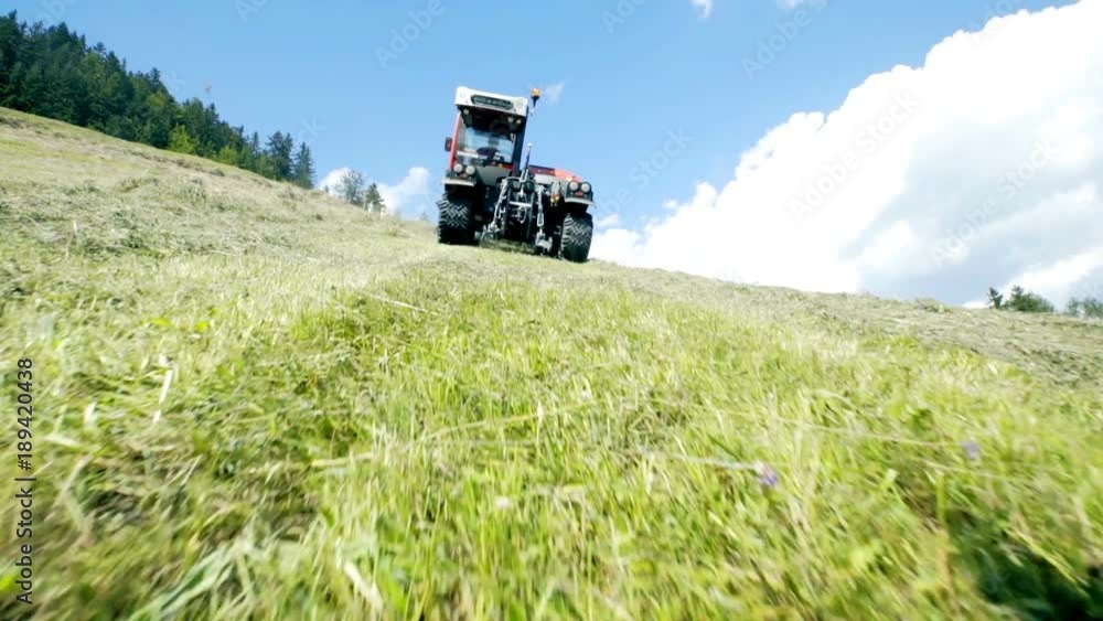 Farmer is driving his tractor uphill and it is organizing hay. Farmer is driving his tractor uphill and it is organizing hay.