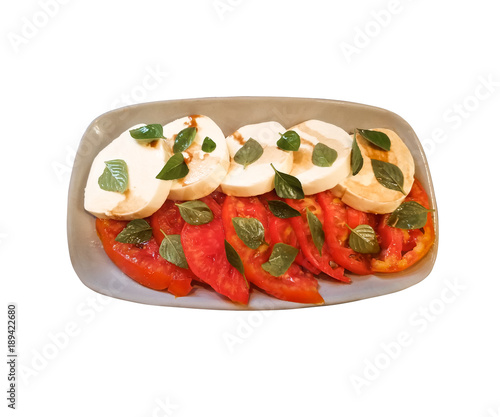 Isolated caprese salad of sliced tomatoes and mozzarella cheese rounds drizzled with balsamic vinegar and sprinkled with basil leaves