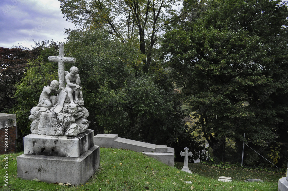 Statue of Two Angel Children with a Cross in a Cemetery Statue of Two Angel Children with a Cross in a Cemetery