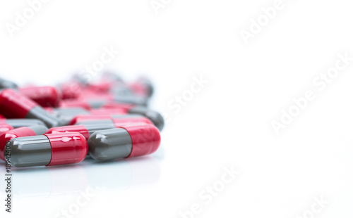 Macro shot detail selective focus of red and grey capsule pills isolated on white background with copy space for text. Migraine prophylaxis treatment concept. photo