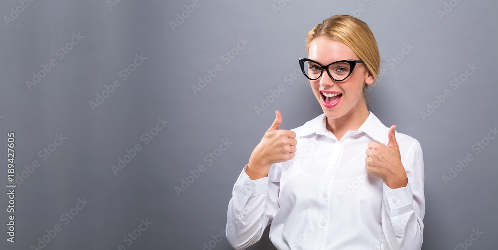 Happy young woman giving thumbs up on a solid background Happy young woman giving thumbs up on a solid background