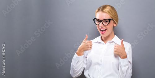 Happy young woman giving thumbs up on a solid background