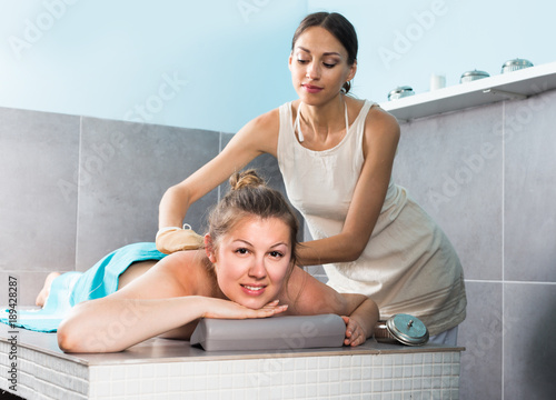 Portrait of cheerful woman which is lying on massage table