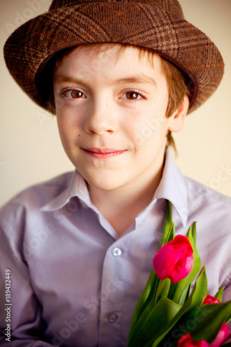 Handsome young boy wearing hat holding tulips/Portrait of handsome teenger wearing hat holding tulips photo