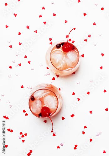 Festive pink cocktail for Valentine's day, couple of glasses, white background with hearts, top view