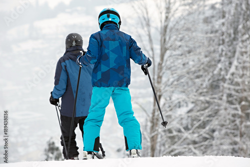 Skiers in winter forest mountains, background