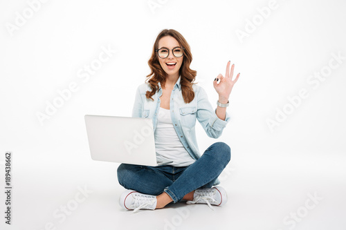 Fotografi Portrait of a smiling casual girl holding laptop computer