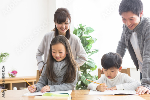 勉強する子供と勉強を見る親