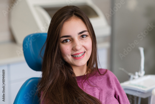 Beautiful girl with braces smiles in dentistry. photo
