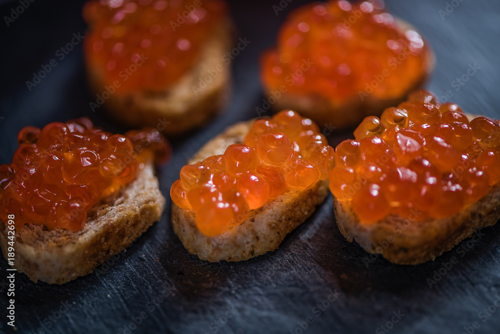 red caviar in crispy baquette on black ston background red caviar in crispy baquette on black ston background