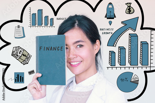 Finance and saving concept- portrait head shot of young asian businesswoman holding fianance text book  smiling  with mixed finance doodles photo