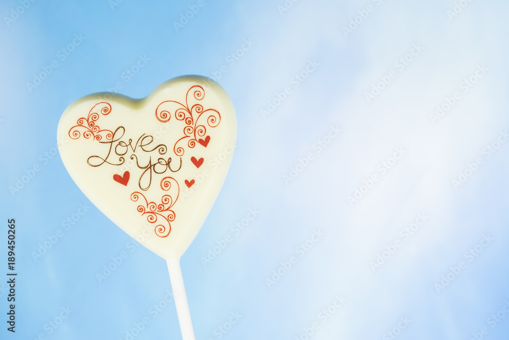 Chocolate heart with the inscription Love you, blue sky background